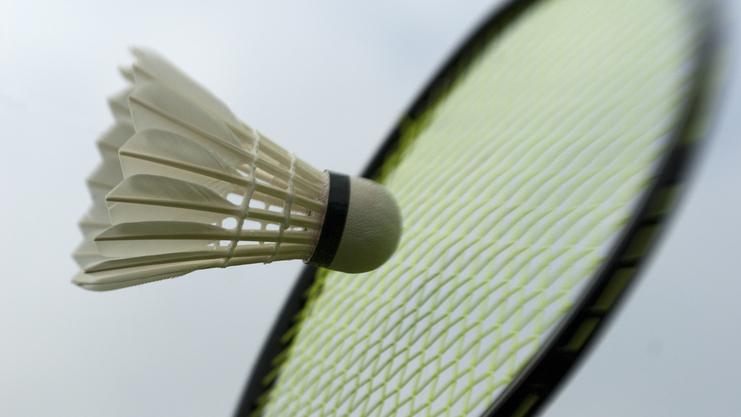 Nahaufnahme eines Federballs, der in Richtung eines Badmintonschlägers fliegt. Hintergrund unscharf.